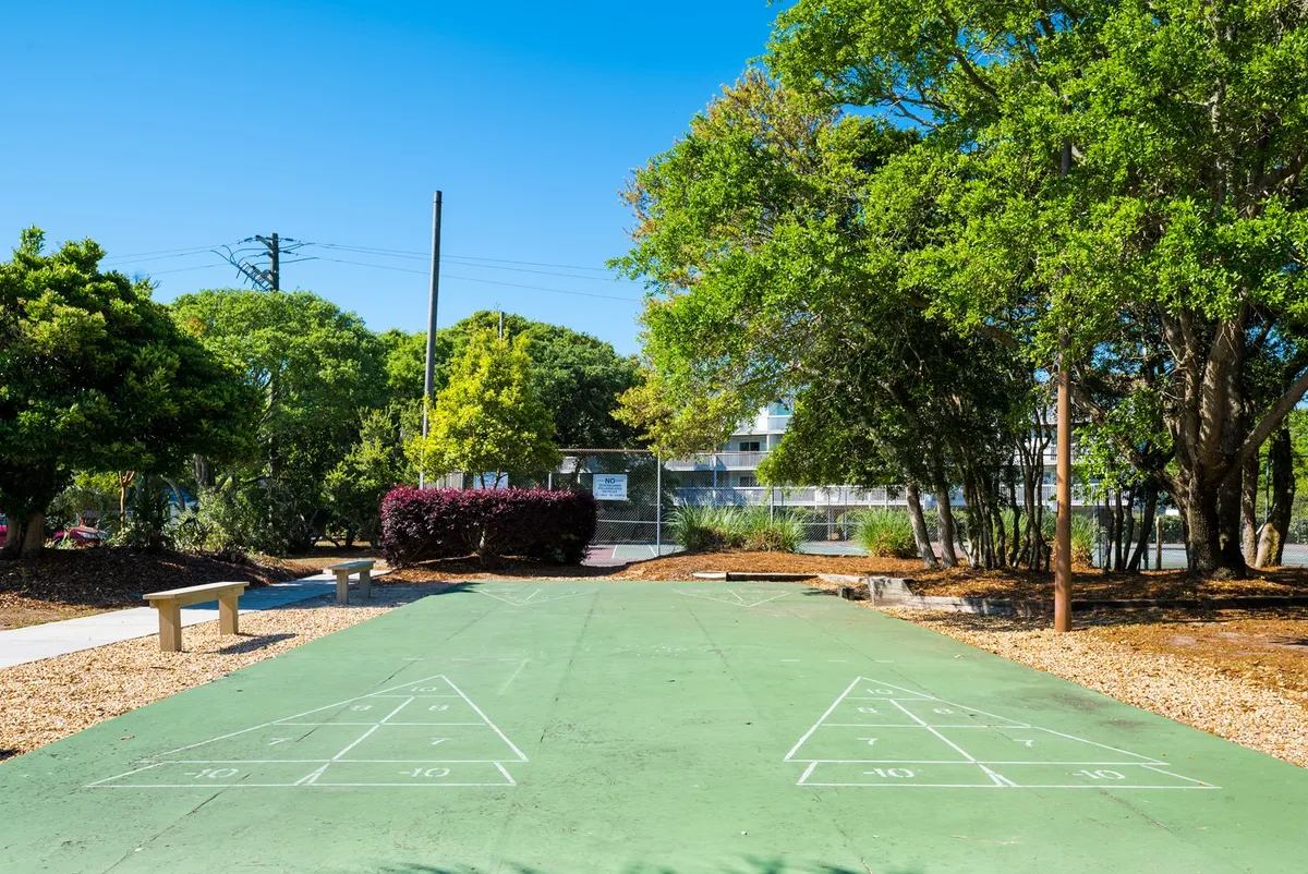 An inviting exterior shot of the shuffleboard court, surrounded by trees and benches. The playful outdoor area encourages friendly competition and relaxed family time in the resort’s natural surroundings.