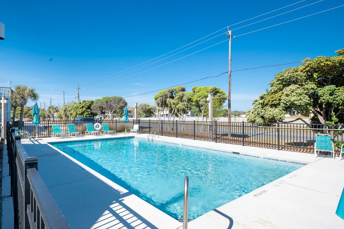 A lively pool scene surrounded by lush greenery and plenty of lounge chairs, perfect for group relaxation, sunbathing, or gathering by the water. The scene evokes cheerful, social energy ideal for a group getaway.