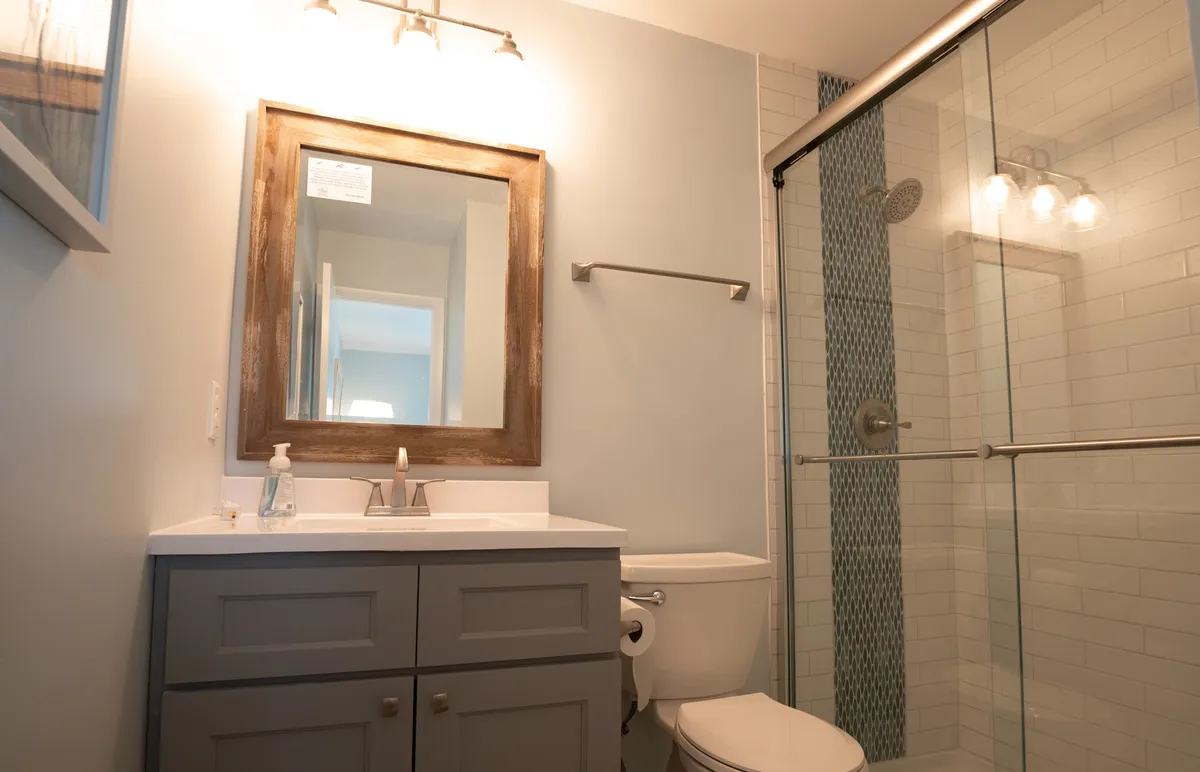 A spa-like bathroom with a glass-enclosed, fully tiled walk-in shower, modern vanity, large mirror, and ambient lighting. The atmosphere is fresh and inviting—perfect for unwinding after a sun-filled day.