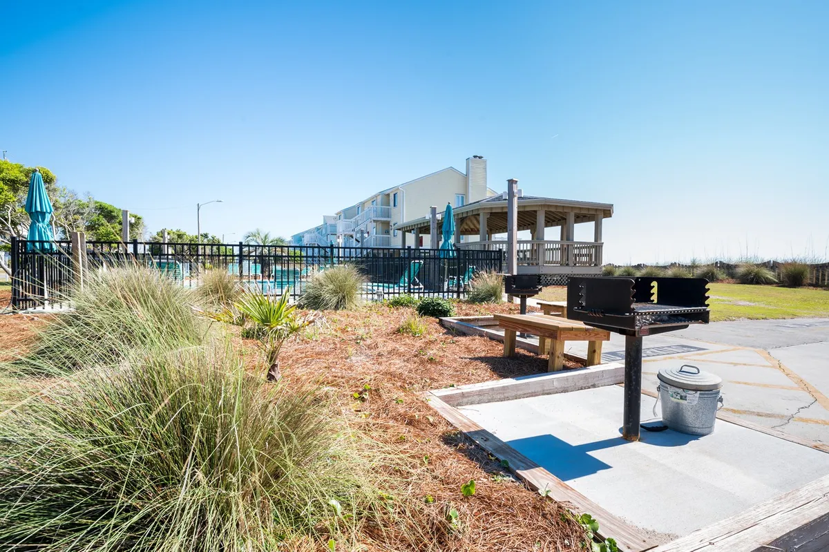 This image shows a barbecue grill and picnic table situated beside a pool area and landscaped garden, creating a lively spot for outdoor dining and social gatherings.